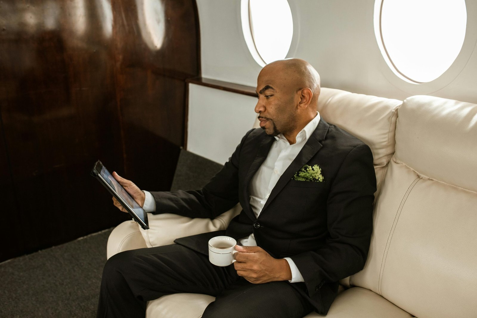 pexels-photo-5778557-5778557 Businessman in formal attire holding tablet and coffee, sitting in private jet.