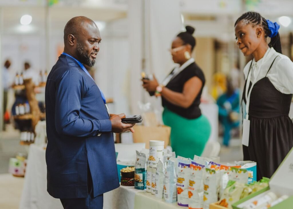 Business professionals interacting at a trade show in Accra, Ghana, showcasing products and engaging in conversation.