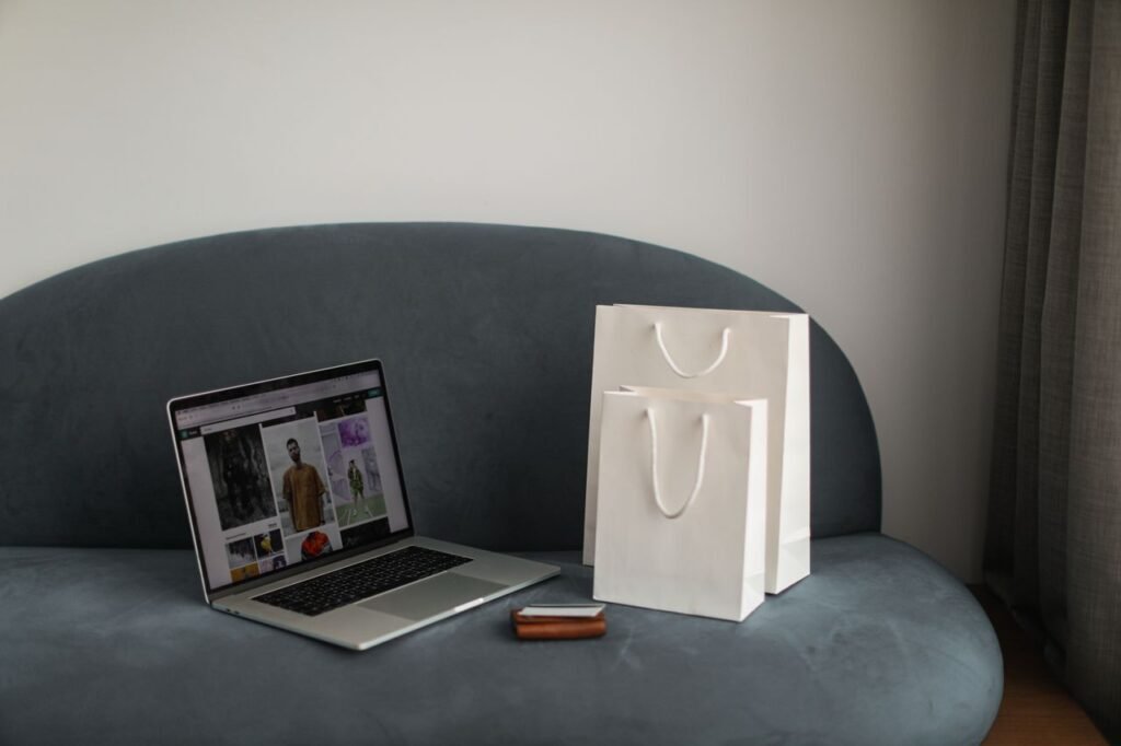 Online shopping setup with a laptop and shopping bags on a stylish couch.