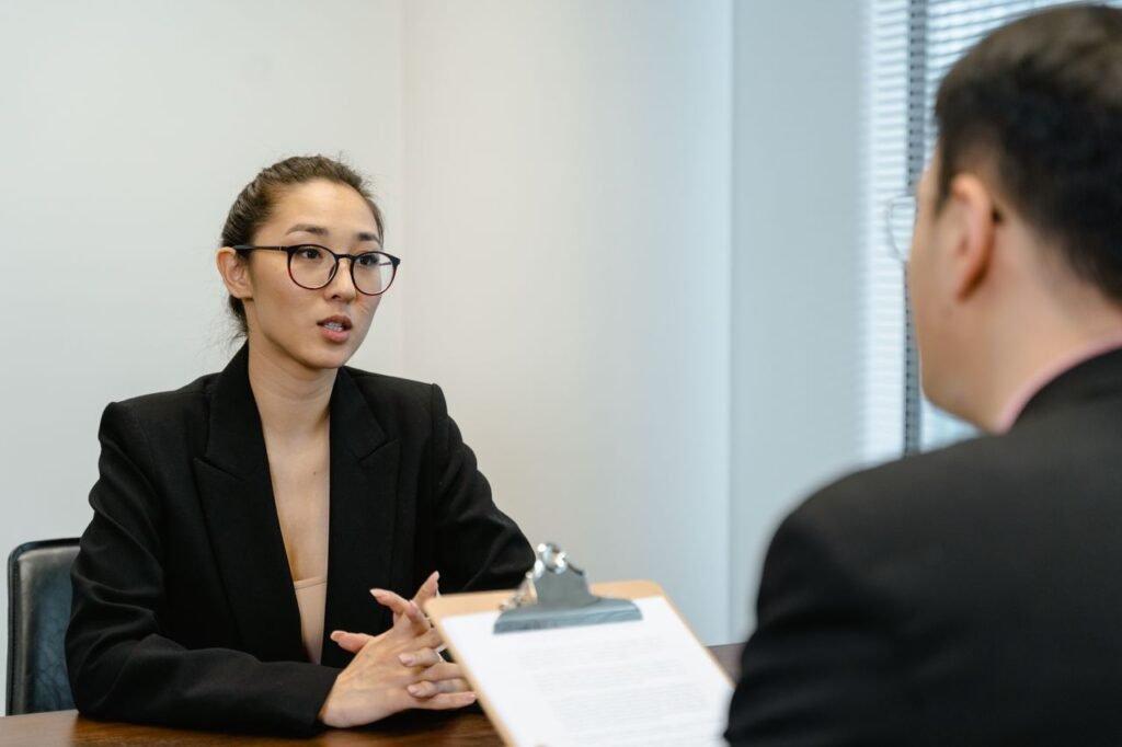 A focused interview scene in an office environment with business attire and a clipboard.