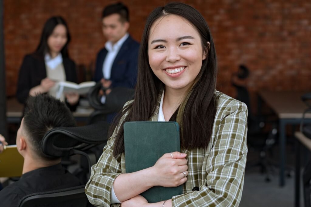 Smiling woman in a professional office environment holding a tablet, conveying confidence and professionalism.
